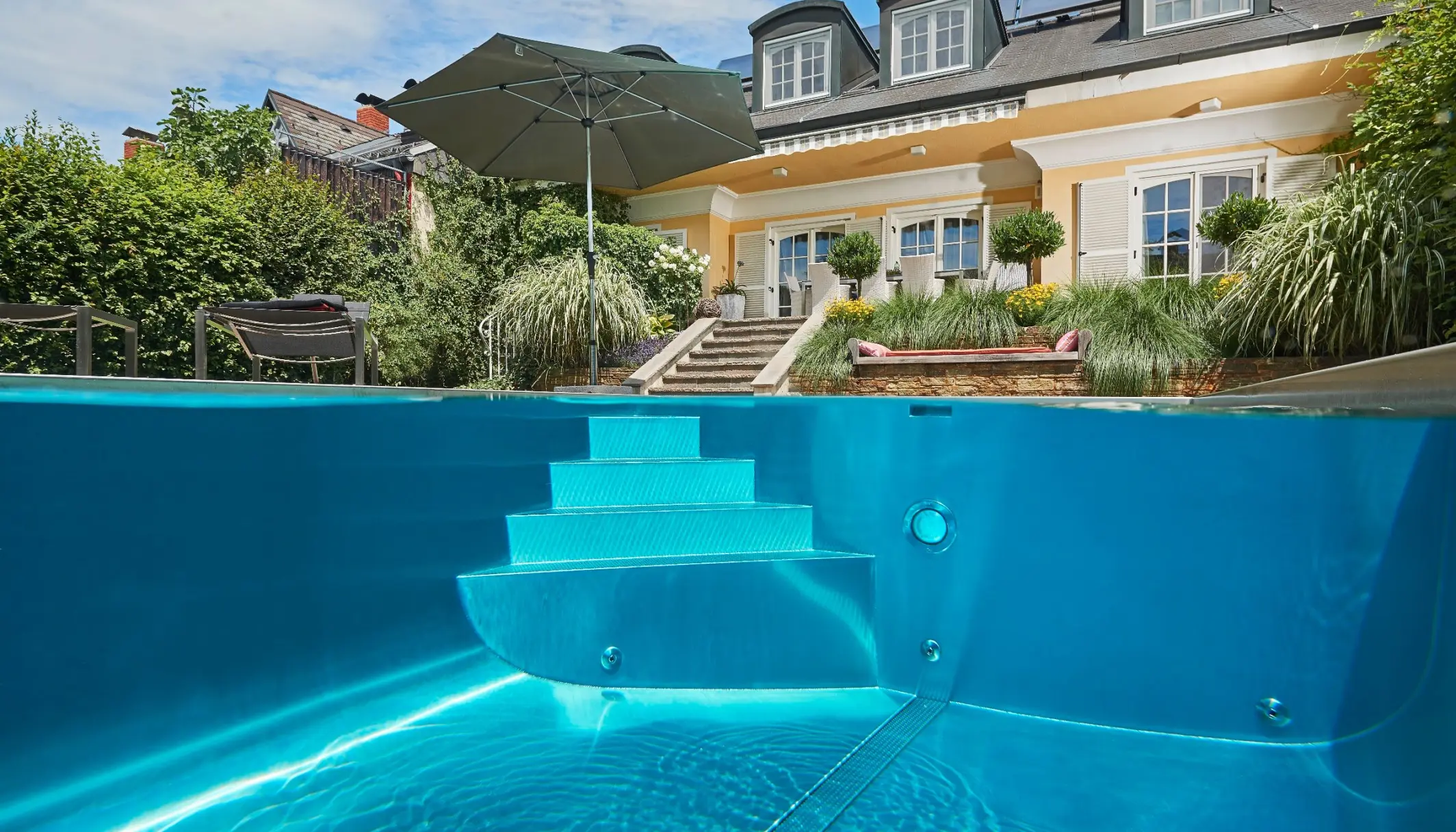 Edelstahl-Fertigbecken Newave von Polytherm mit großzügiger Treppe im klassischen Garten