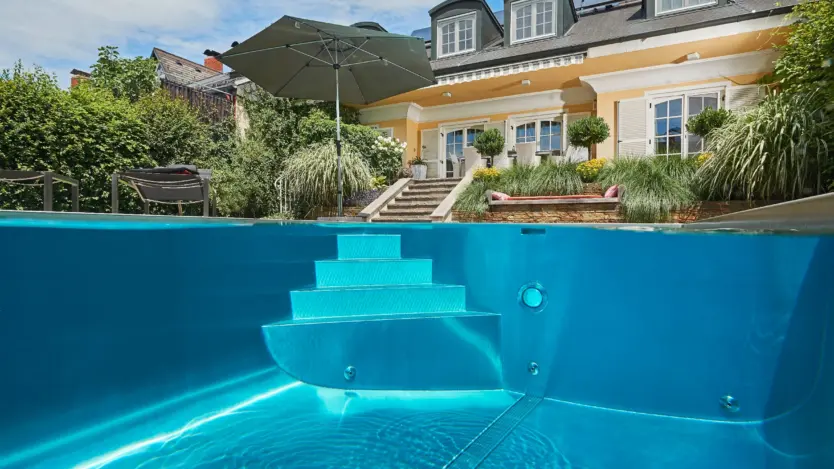Edelstahl-Fertigbecken Newave von Polytherm mit großzügiger Treppe im klassischen Garten